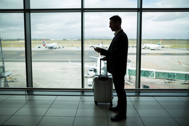 businessman with luggage and his phone in an airport