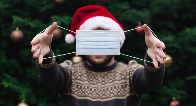 a man holding a mask in front of a christmas tree